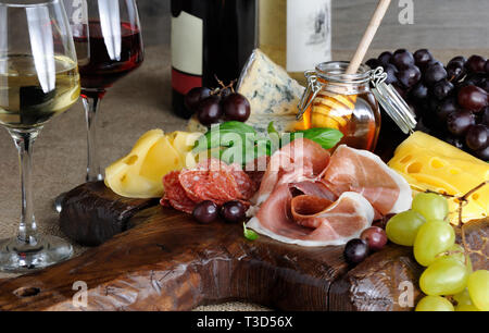 Antipasto catering platter with jerky bacon,  prosciutto, salami, cheese    and grapes on a wooden background Stock Photo