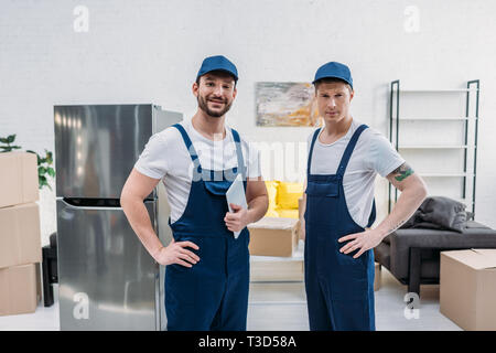 two handsome movers with digital tablet looking at camera in apartment Stock Photo