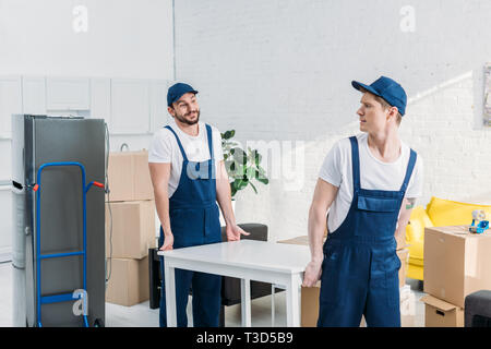 two movers in uniform transporting table in apartment Stock Photo