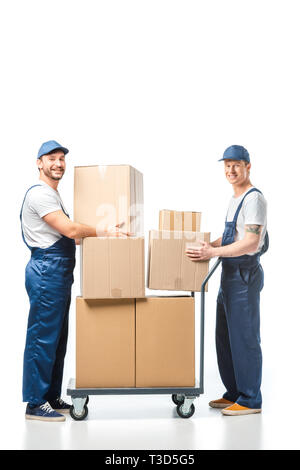 two handsome movers looking at camera while transporting cardboard boxes with hand truck on white Stock Photo