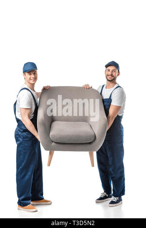 two smiling movers looking at camera and transporting grey armchair isolated on white Stock Photo