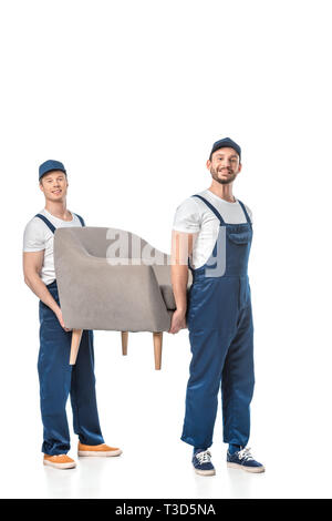 two smiling movers looking at camera and transporting grey armchair isolated on white Stock Photo