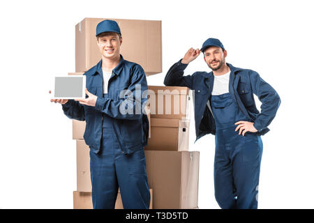 two movers with cardboard boxes looking at camera and presenting digital tablet with blank screen isolated on white Stock Photo