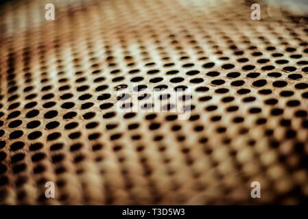 Perforated brown rusty iron sheet texture. Surface with depth of field, abstract industrial mesh. Horizontal light background Stock Photo
