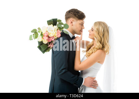 beautiful bride hugging happy bridegroom and showing hush sign on his lips isolated on white Stock Photo