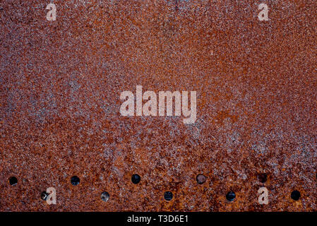 Texture of old completely rusty metal with row of holes in down side Stock Photo