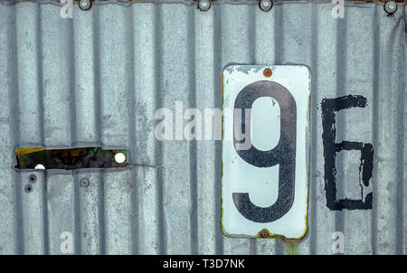 White Shabby Metal Plate With Black Nuber Nine and Six Nailed On Corrugated Iron Sheet Stock Photo