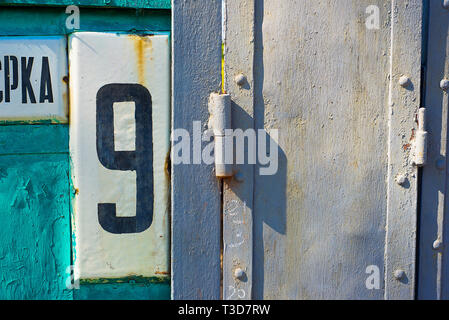 White Shabby Metal Plate With Black Nuber Nine Nailed On Iron Sheet Beside Steel door Stock Photo