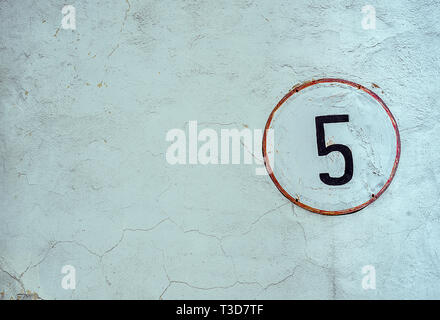 White Shabby Round Metal Plate With Black Nuber Five, Nailed On Whitewashed Concrete Old Wall Stock Photo