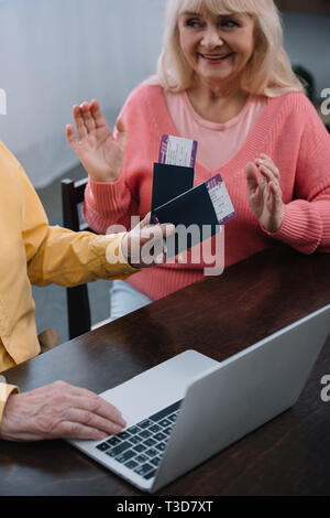 senior man holding air tickets and passports near surprised woman at home Stock Photo