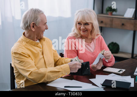 smiling senior couple holding wallet and envelope with money at home Stock Photo