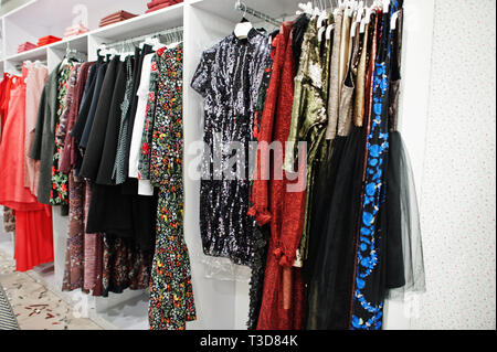 Female colorful clothing evening dresses set of on the racks in clothing store brand new modern boutique. Stock Photo