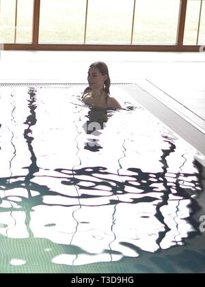 swimming pool in wellness with reflection window and with floating woman Stock Photo