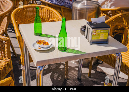 Valencia,Spain - April 07, 2019:  Two empty beer bottles and snacks. Table at terrace in Valencia city. Stock Photo