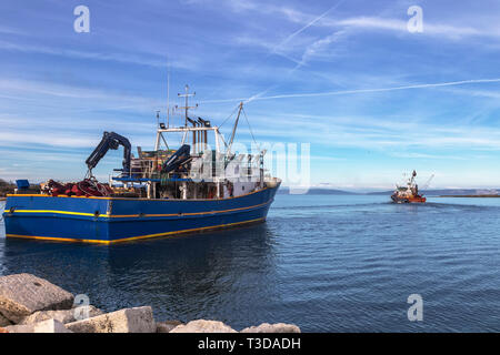 two fishing trawlers leave the port in early evening Stock Photo