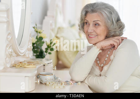 Happy senior woman sitting near dressing table Stock Photo