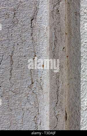 Vertical cracks in the stone of a wall that contrast with the shadow caused by the ledge on the stone itself. Stock Photo