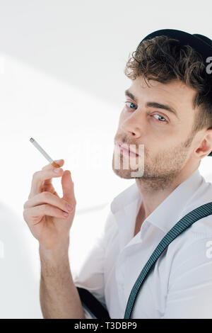 handsome man holding cigarette and looking at camera Stock Photo