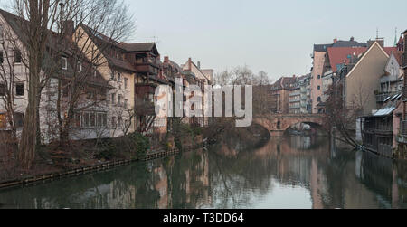 Houses and a bridge reflected in a river in the old town of Nuremberg seen from Henkersteg covered bridge across Pegnitz river - Germany Stock Photo
