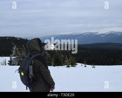 Mountain traveler with crystal ball looks around in mountains. Stock Photo