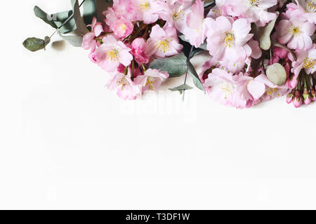 Closeup of decorative banner made of pink Japanese cherry blossoms and eucalyptus branches. Styled stock photo. Spring, Easter feminine floral composi Stock Photo