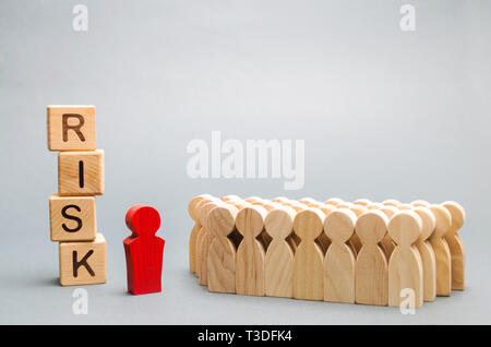 Wooden blocks with the word Risk and a team with a leader. Business concept of teamwork, crisis solution and problem management. Business planning. In Stock Photo