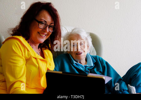An elderly woman with her mature daughter using an ipad - John Gollop Stock Photo