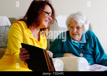 An elderly woman with her mature daughter using an ipad - John Gollop Stock Photo