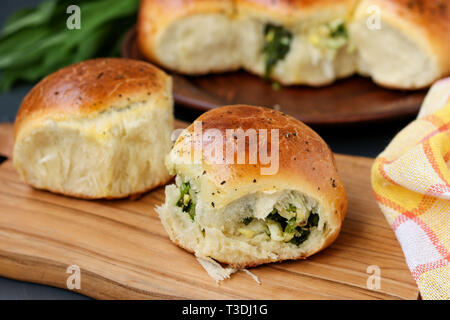 Yeast buns filled with greens and boiled eggs are located on a wooden board Stock Photo