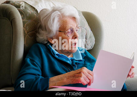 Real life image of an elderly woman reading a greetings card - John Gollop Stock Photo