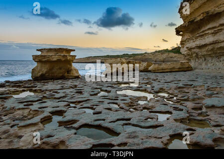 Rock formations at St. Peter's Pool at sunset near Marsaxlokk, Malta. Unusual limestone rocks as a result of natural wind and water erosion at Maltese Stock Photo