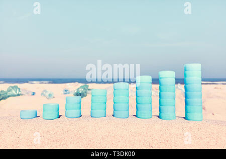 Chart made of plastic bottles caps on sand showing the increase in use of plastic products, color toned picture, selective focus. Stock Photo