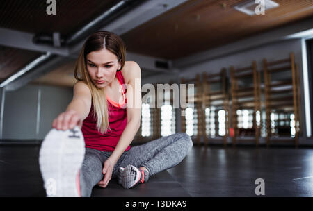 A portrait of young girl or woman doing exercise in a gym. Stock Photo