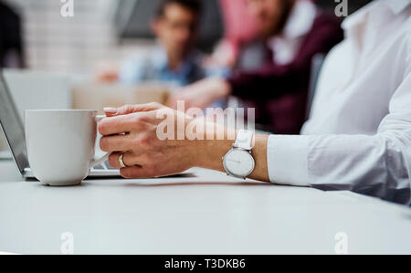 A midsection of businesswoman with a cup of coffee working in office, using laptop. Stock Photo