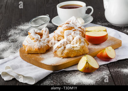 Biscuit rolls filled with jam with powdered sugar on top on plate over wooden table Stock Photo