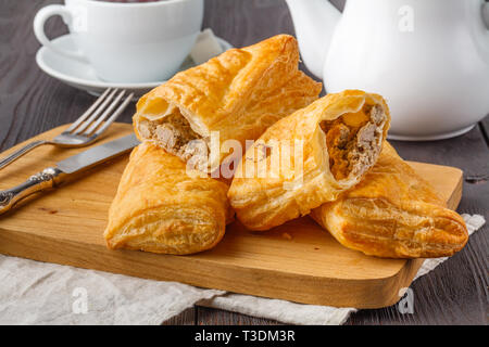 Puff pastry triangles filled with feta cheese and spinach on wooden table Stock Photo