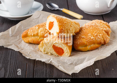 Biscuit rolls filled with jam with powdered sugar on top on plate over wooden table Stock Photo