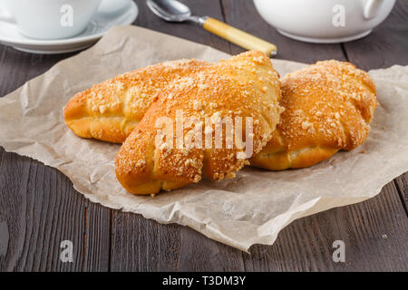 Biscuit rolls filled with jam with powdered sugar on top on plate over wooden table Stock Photo