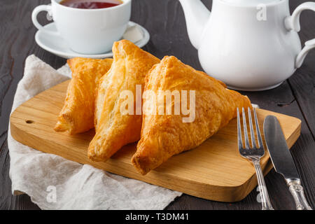 Puff pastry triangles filled with feta cheese and spinach on wooden table Stock Photo