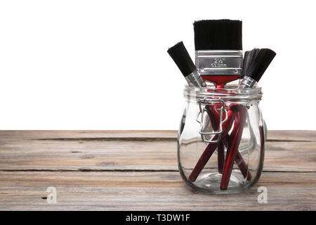 Paint Brushes in Glass Jar on Wooden Background Stock Photo