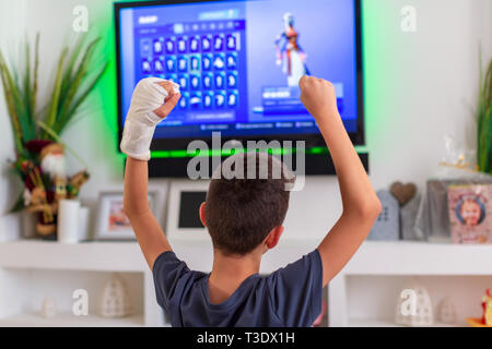 boy with plaster on his hand rejoices victory in a video game Stock Photo