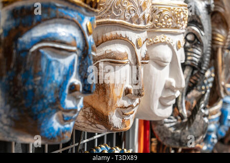 Wooden mask with the image of the Buddha on display for sale on street market in Ubud, Bali, Indonesia. Handicrafts and souvenir shop display, close u Stock Photo