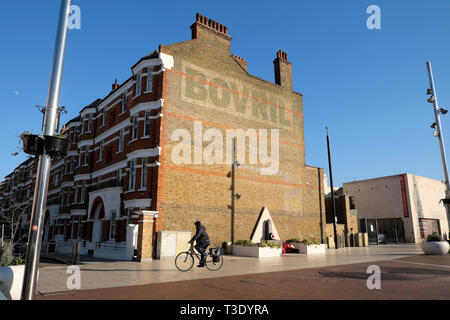 Man on bike cyclist cycling in Windrush Square and the Bovril building next to Black Cultural Centre in Brixton South London England UK  KATHY DEWITT Stock Photo