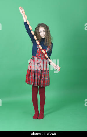 Young girl holds sausages on green background. High resolution photo. Stock Photo