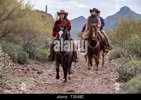 American cowboys ride their mounts in the desert scene around Wickenburg, Arizona Stock Photo