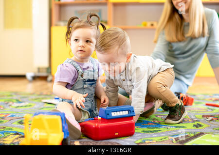 babysitter and kids playing together in nursery or day care centre Stock Photo