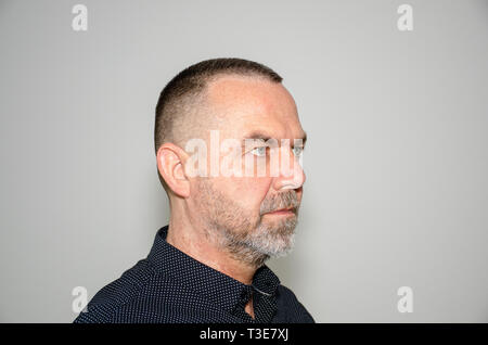 Profile portrait of a bearded middle aged man in stylish dark shirt with short modern haircut looking to the right Stock Photo