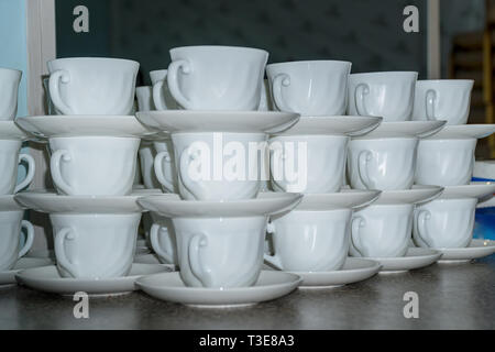 White coffee cups with saucers in stacks Stock Photo