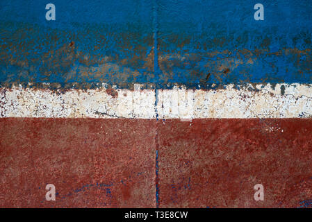 A Close Up Of A Metal Ships Hull Painted In Blue, White and Rusty Red Stripes Stock Photo