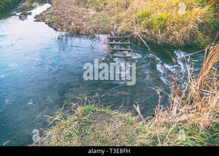 Little river in the autumn. Water flows in a small river. Water flows through a wooden obstacle Stock Photo